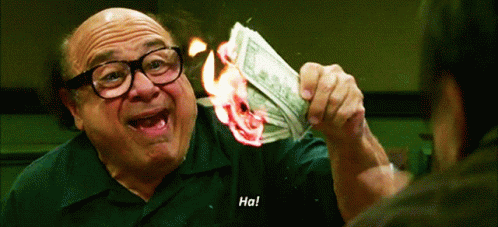A gif of Danny DeVito holding money that is on fire.